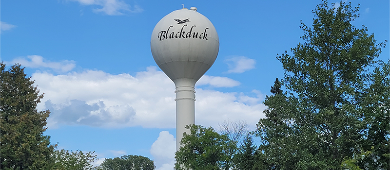 Blackduck water tower with blue sky, clouds and trees in background